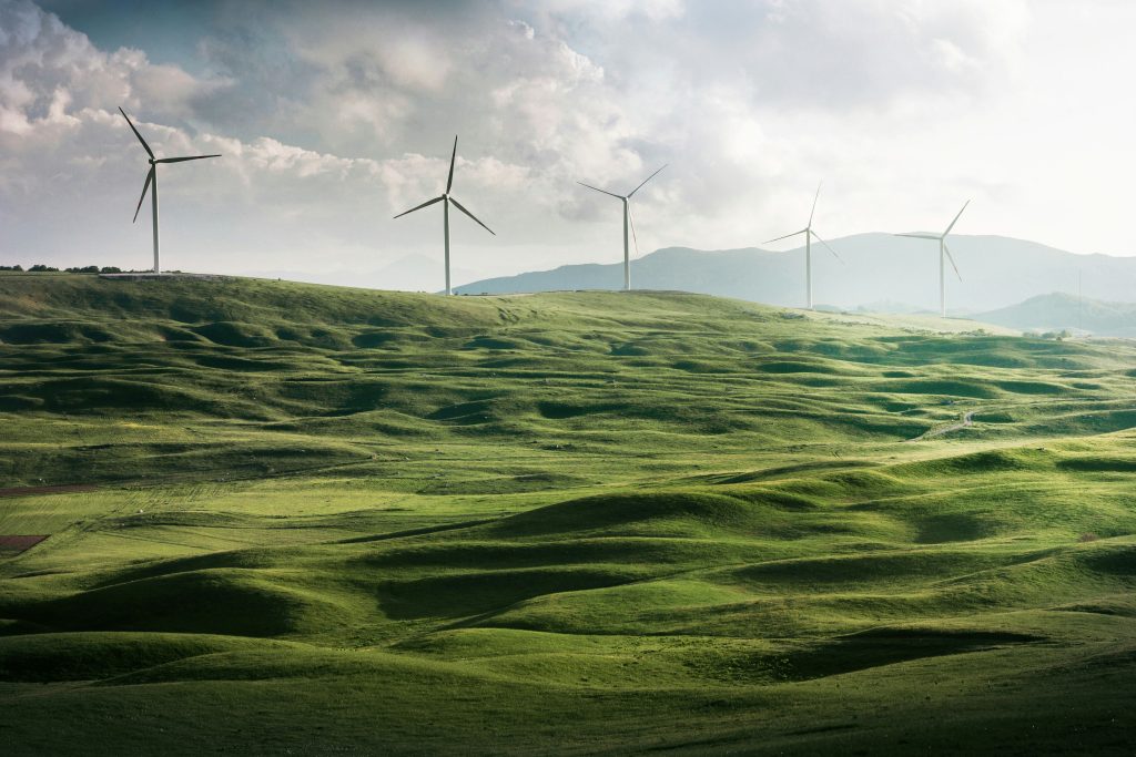 Parque eólico en un valle verde, rodeado de majestuosas montañas, simbolizando la transición energética justa hacia fuentes renovables y sostenibles Parque eólico en un valle verde, rodeado de majestuosas montañas, simbolizando la transición energética justa hacia fuentes renovables y sostenibles