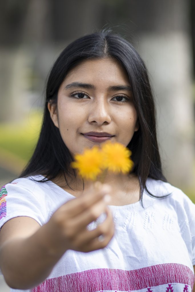 Fátima Abril Zúñiga, sostiene una pequeña flor amarilla